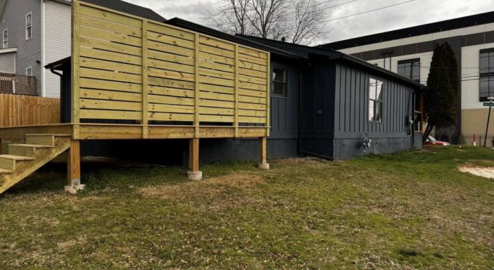 Rear Exterior & Deck – After Renovation Renovated rear exterior with dark siding, wood deck and privacy wall
